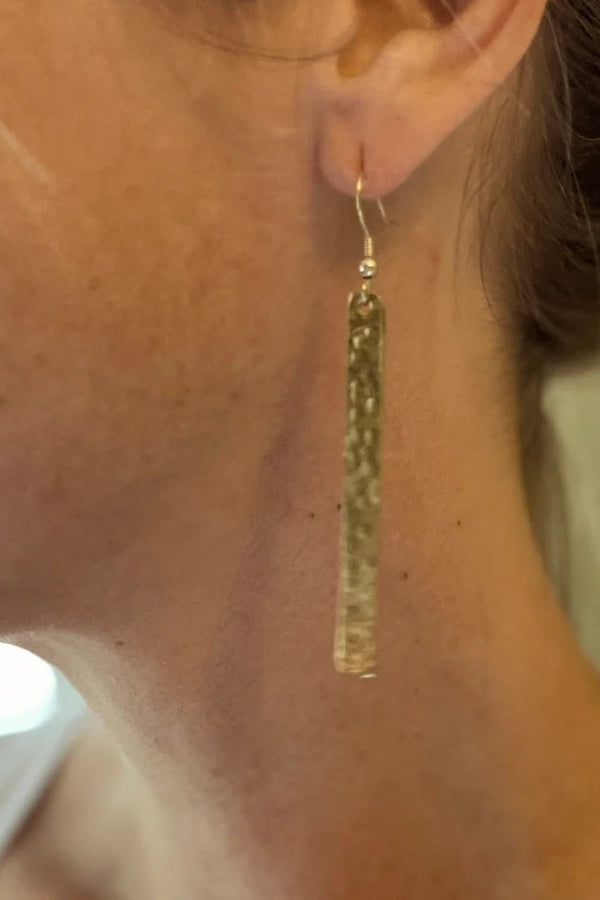 Gold tassel earring worn by a person with a neutral background