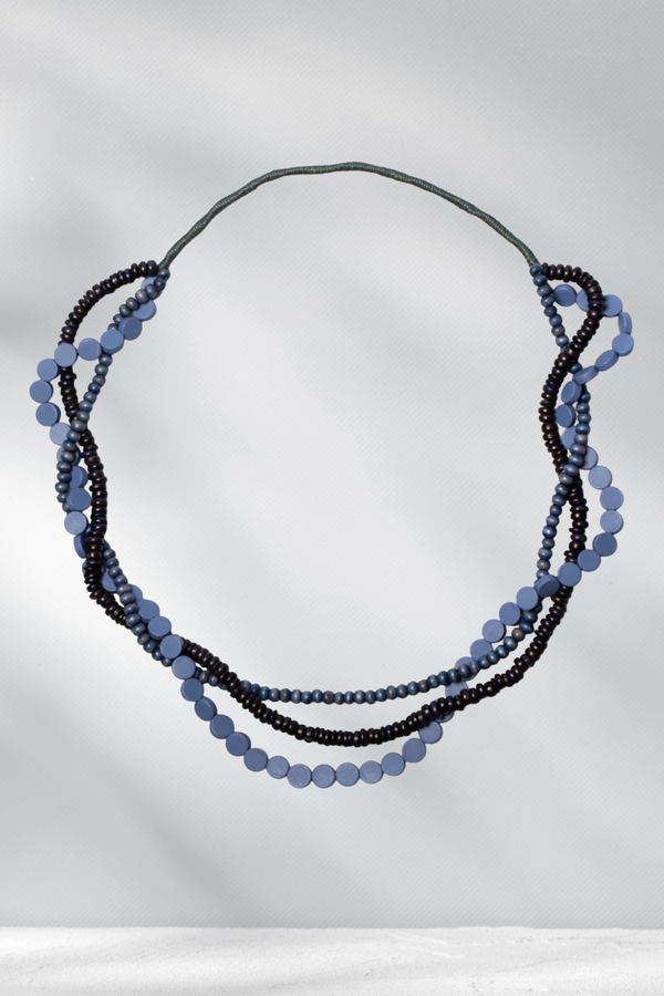 Necklace with blue and black beads on a gray background